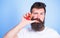 Fresh juice concept. Man drinks strawberry juice suck thumb as drink straw blue background. Hipster bearded holds