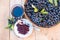 Fresh juice and jam of ripe black chokeberry Aronia melanocarpa in glass and berry in pot on wooden background