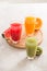 Fresh juices smoothie three glass red green orange tropical fruits water melon, kiwi, orange. Selective focus