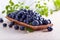 Fresh juicy blueberries with green leaves on a kitchen table .