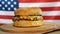 Fresh juicy hamburger rotating on US flag background.
