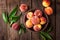 Fresh juicy peaches with leaves on dark wooden rustic background, above view