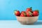 Fresh juicy strawberries in wood bowl on light blue table