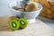 Fresh kiwifruit in the bowl on wooden cutting board.