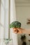 Fresh large broccoli cabbage in hand of human on residential white kitchen. healthy wellness eating habits, vertical, selective