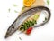 Fresh Largehead hairtail fish,Belt fish decorated with herbs and vegetables on a wooden pad.Selective focus