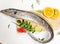 Fresh Largehead hairtail fish,Belt fish decorated with herbs and vegetables on a wooden pad.Selective focus