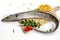 Fresh Largehead hairtail fish,Belt fish decorated with herbs and vegetables on a wooden pad.Selective focus