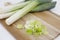 Fresh Leeks and leek round cuttings in a wooden board in a white background