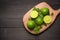 Fresh limes on cutting board on wooden table. Top view, background.