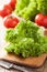 Fresh lollo leaves and tomatoes on chopping board for salad