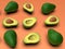 Fresh looking green avocado fruits, whole and cut in half, on pink