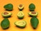 Fresh looking green avocado fruits, whole and cut, on orange