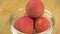 Fresh lychee fruit in shell rotate in glass bowl in macro. Lychee berries for making lemonade and refreshing drink