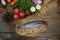 Fresh mackerel isolated on a wooden cutting board with vegetables, sprouted beans and herbs and spices