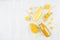 Fresh mango and orange juices in glass bottles with sliced fruit, straws on white wooden board, top view, copy space, template