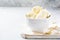 Fresh mascarpone cheese in a white bowl for making Italian tiramisu dessert on light background. Selective focus