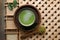 Fresh matcha tea in bowl and spoon with powder on wooden tray