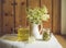 Fresh Meadowsweet, Filipendula ulmaria in jug shape vase and it`s herbal tea in glass, tea powder in jar. Indoors country home.