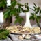 Fresh meat dumplings plate at kitchen table with green plants in vase on blurred background. Convenient food preparation