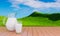 Fresh milk in clear glass and milk jug placed on the slatted floor. Bright green grasslands with hills, bright skies, white clouds