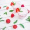 Fresh milkshake. Strawberry smoothie and pattern made of strawberries and mint leaves on white wood background. Flat lay. Top view