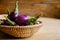 Fresh mini purple eggplant in the basket on wooden background