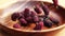 Fresh mulberries fall into a wooden bowl on a wooden board