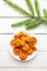 Fresh mushrooms orange milkcap or false saffron milkcap, Lactarius deterrimus on plate, white wood board background with spruce.