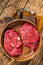Fresh Mutton chop leg steaks, uncooked lamb meat with herbs. Wooden background. Top view
