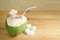 Fresh natural coconut juice in coconut shell with Plumeria flower isolated on wooden table