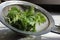 Fresh nettle leaves in a strainer on a white wooden table. Ingredient for healthy vitamin herbal te