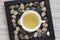 Fresh oolong tea in white pot on stones in square tray on light striped table