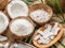 Fresh opened coconuts along with coconut slices, flakes and coconut leaves on a wooden table