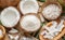 Fresh opened coconuts along with coconut slices, flakes and coconut leaves on a wooden table