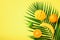 Fresh orange, banana, pineapple, mango smoothie and juicy fruits on palm leaves over yellow background. Detox summer