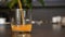 Fresh Orange Juice Pouring Into Glass Standing on Table, Bar on Background