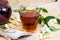 Fresh organic aromatic glass herbal tea cup with white jasmine flowers on light background.