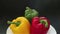 Fresh organic bell peppers on white plate on black background panning shot