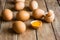 Fresh organic brown eggs scattered on wood table, cracked shells, open yolk