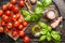 Fresh organic cherry tomatoes with basil leaves and olives oil on rustic kitchen table