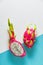 Fresh organic dragonfruit pitaya or pitahaya cut in half on two tone split blue mint and white background. Creative flat layout