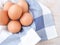 Fresh organic eggs on a white dishcloth with blue straight stripes.