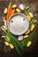 Fresh organic garden vegetables around empty colander bowl on dark rustic wooden background