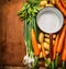 Fresh organic garden vegetables around empty old cooking pan on wooden background, top view