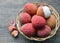 Fresh organic lychees in a basket on old wooden background.Exotic tropical lychee fruits.