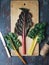 Fresh organic rainbow swiss chard leaves on dark wooden table, top view