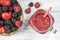 Fresh organic red smoothie in glass mug on white table, close up, top view. Refreshing summer fruit drink. Blackberry, raspberry