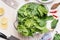 Fresh organic spinach leaves in colander on kitchen table background, top view