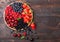 Fresh organic summer berries mix in round wooden tray on dark wooden table background. Raspberries, strawberries, blueberries,